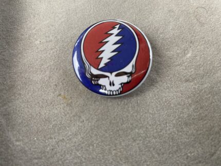 A red white and blue button with a skull on it