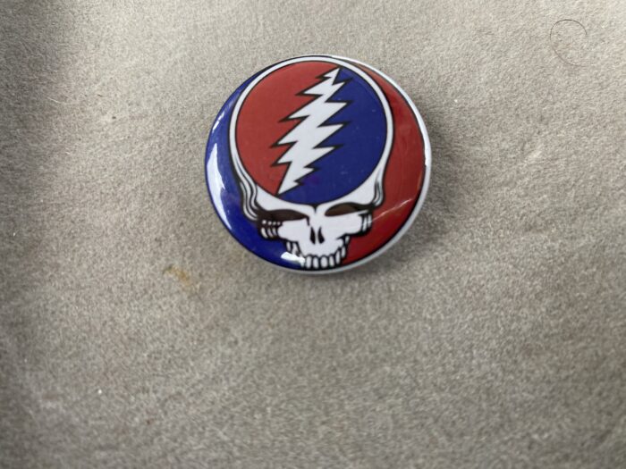 A red white and blue button with a skull on it