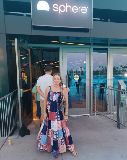 A woman in a colorful dress standing outside of a building.