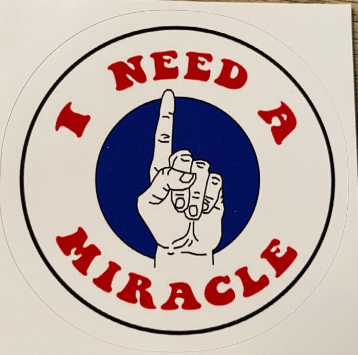 A sticker that says i need a miracle with an asl sign.