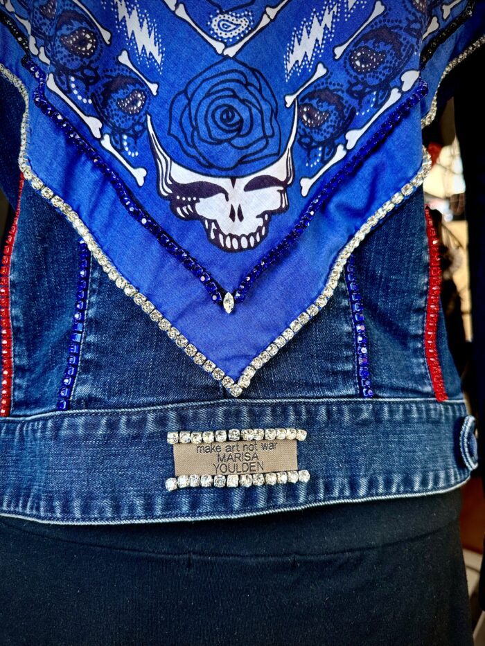 A blue jean vest with a skull and roses design.