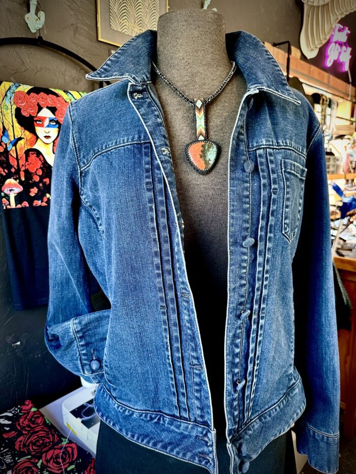 A woman wearing a jean jacket with a heart necklace.