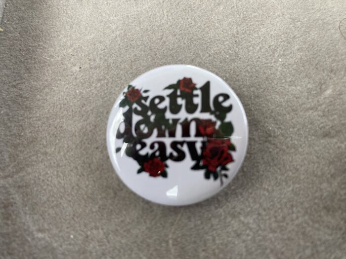 A button that says settle down easy with red flowers.