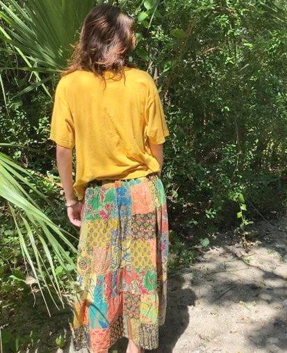 Woman in yellow shirt and patterned skirt.