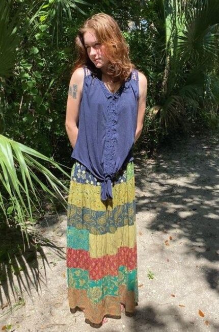 Woman wearing blue top and patterned skirt.