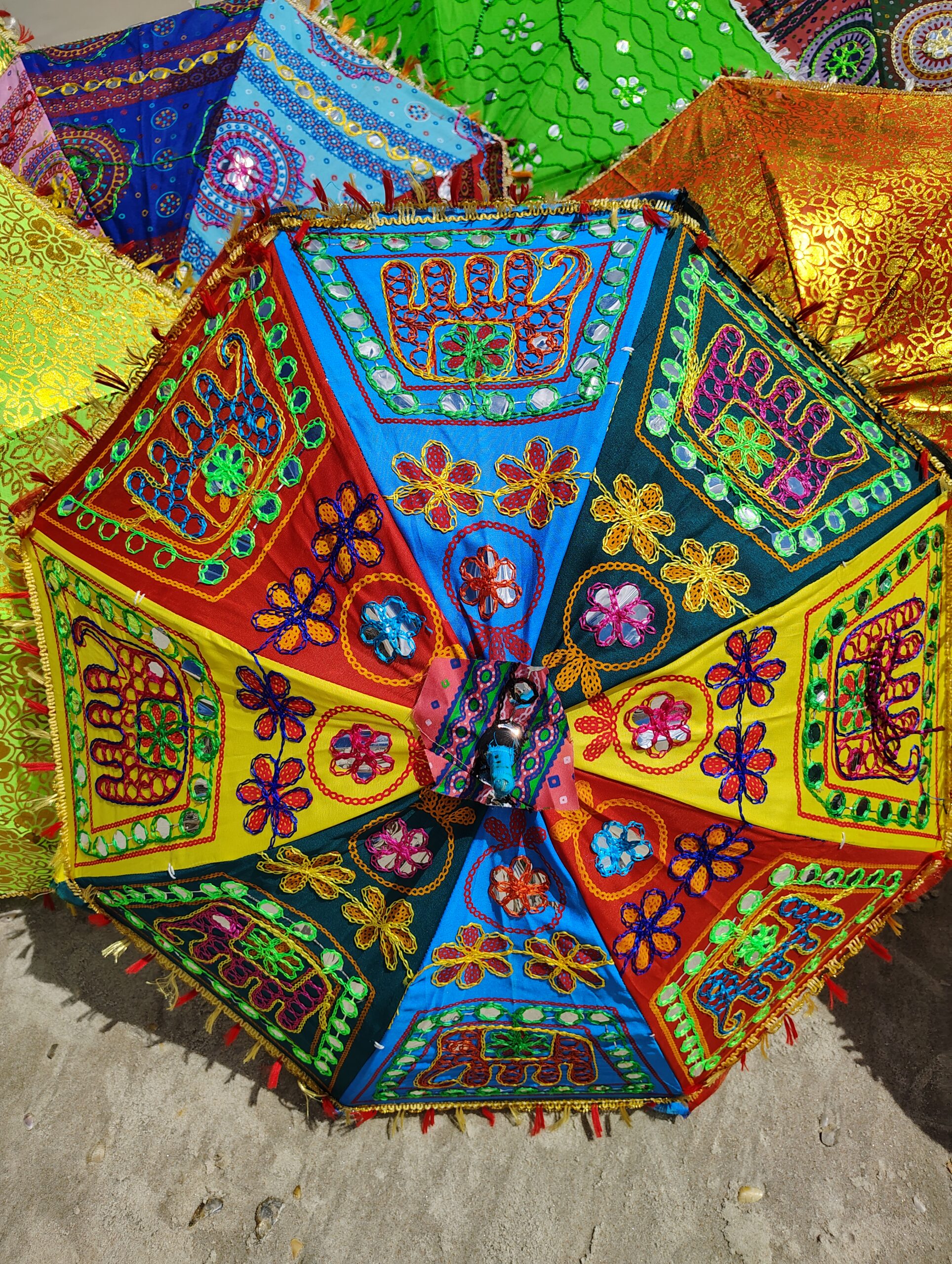 Colorful embroidered umbrella on sand.