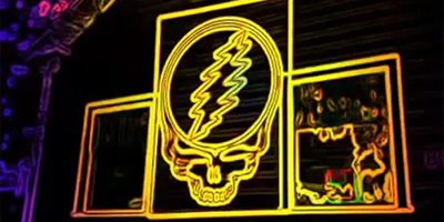 Grateful Dead logo with yellow neon glow.