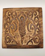 Carved wooden plaque with intricate swirls.