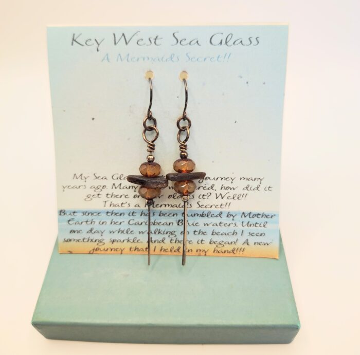 Sea glass earrings on a blue card.