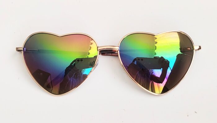 Heart-shaped iridescent sunglasses with reflection.