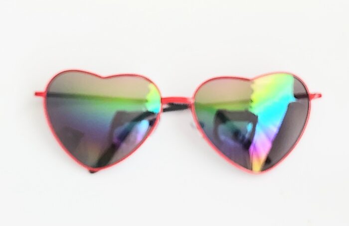 Red heart-shaped sunglasses with iridescent lenses.