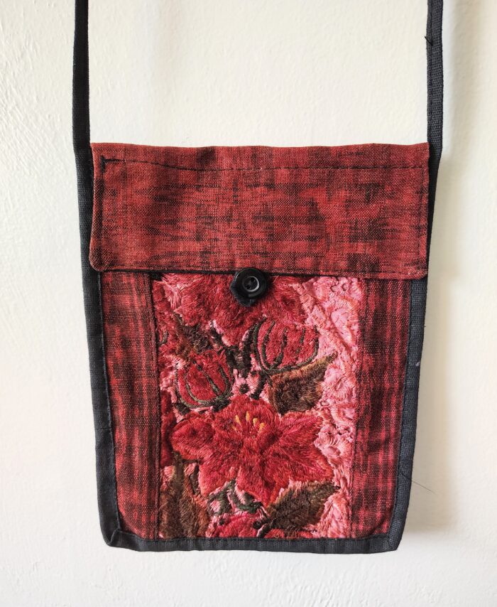 Red embroidered floral fabric bag with strap.