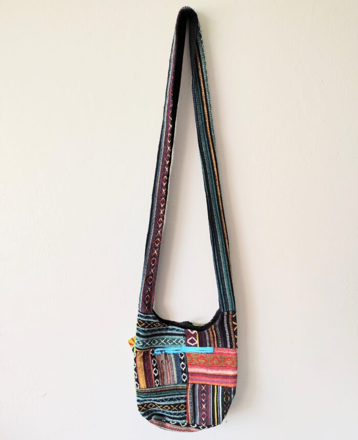 Colorful patterned shoulder bag on white wall.