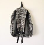 Black and white patterned backpack hanging on wall.