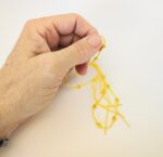 Hand holding yellow beaded string.