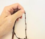 Hand holding brown beaded cord.