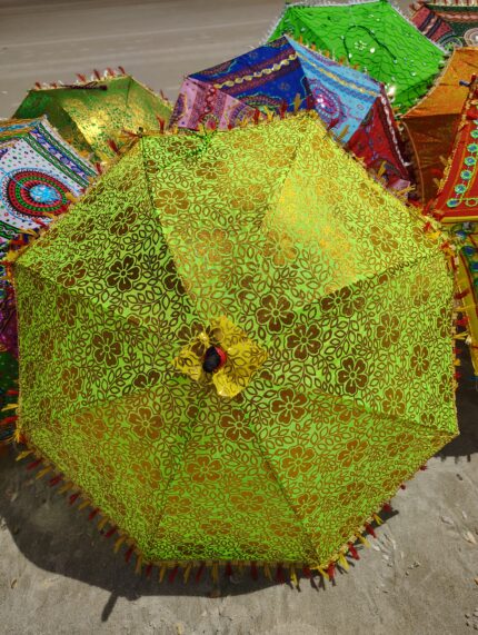 Green floral patterned umbrella on sand.