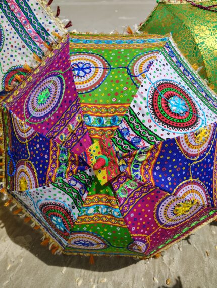 Colorful patterned umbrella on sand.