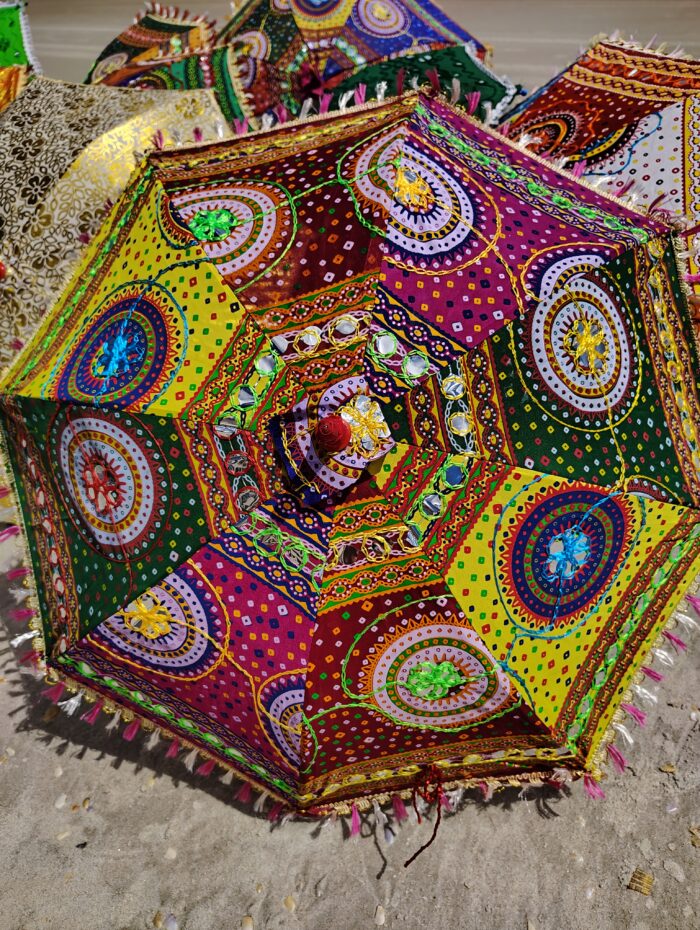 Colorful embroidered umbrella on sand.