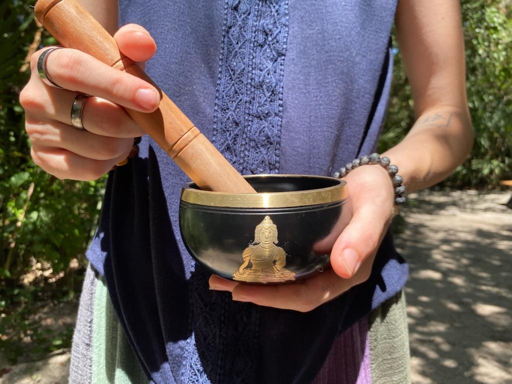 Person holding a black singing bowl with a Buddha.