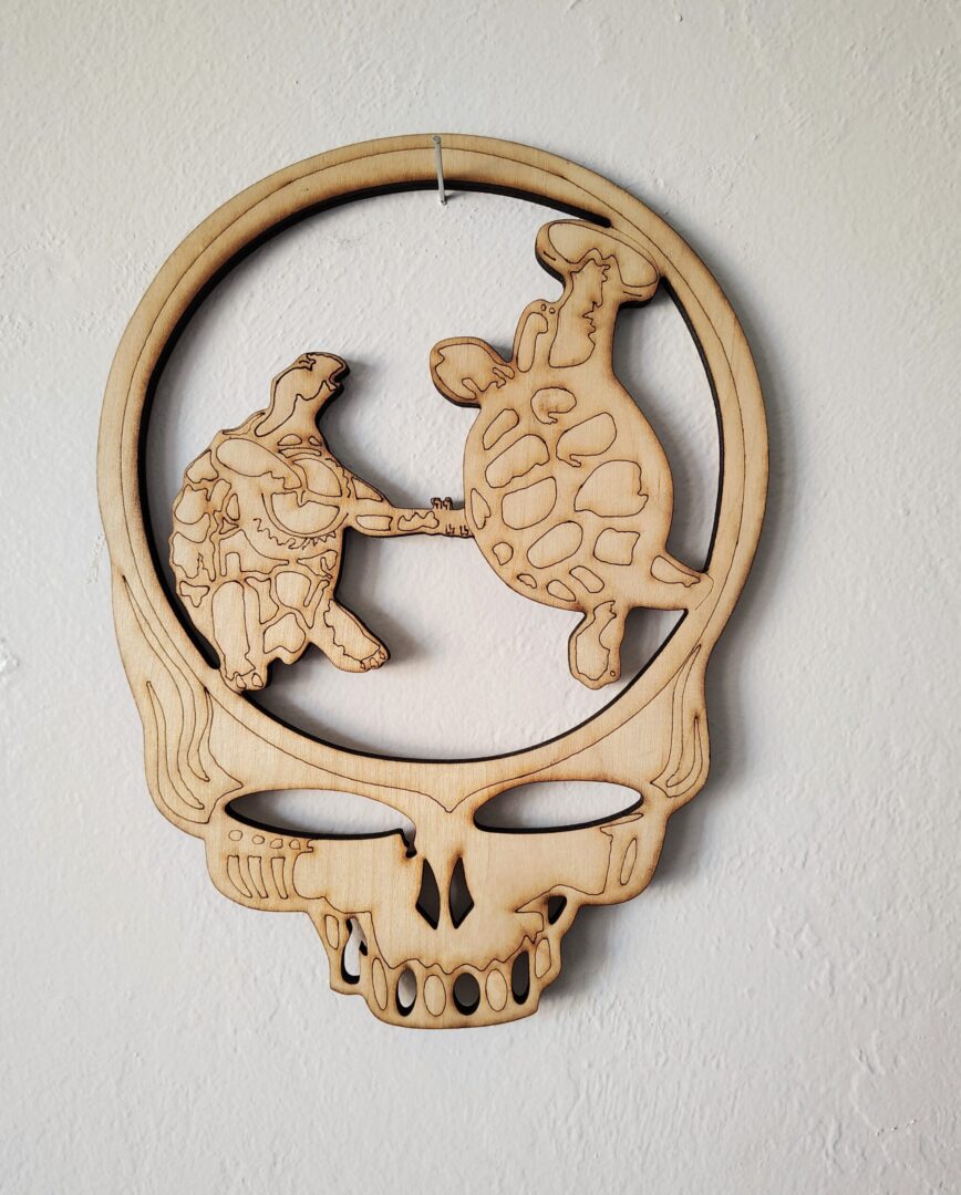 Wooden cutout of two turtles in skull.