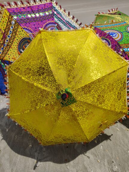 Yellow floral patterned umbrella on sand.