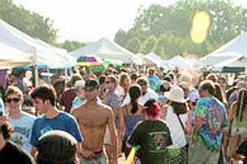 Crowded outdoor market with tents and people.